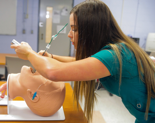 female allied health studetn placing a tube in a dummy's mouth