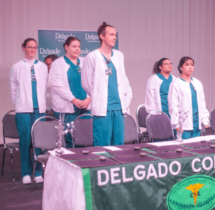 Nursing Students standing at Convocation ceremony in front of awards table. 