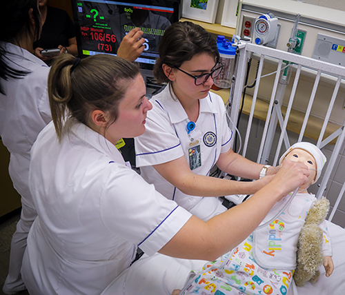 two female nurses practicing on a child dummy