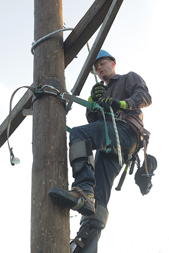 student on a pole setting up an electric line