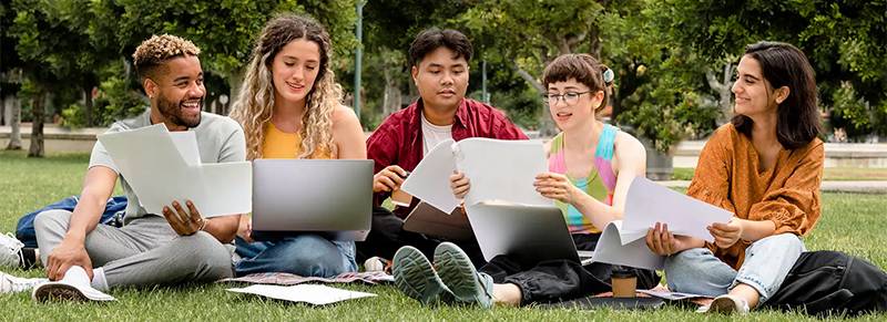 diverse group of students sitting on grass with tagline Education That Works