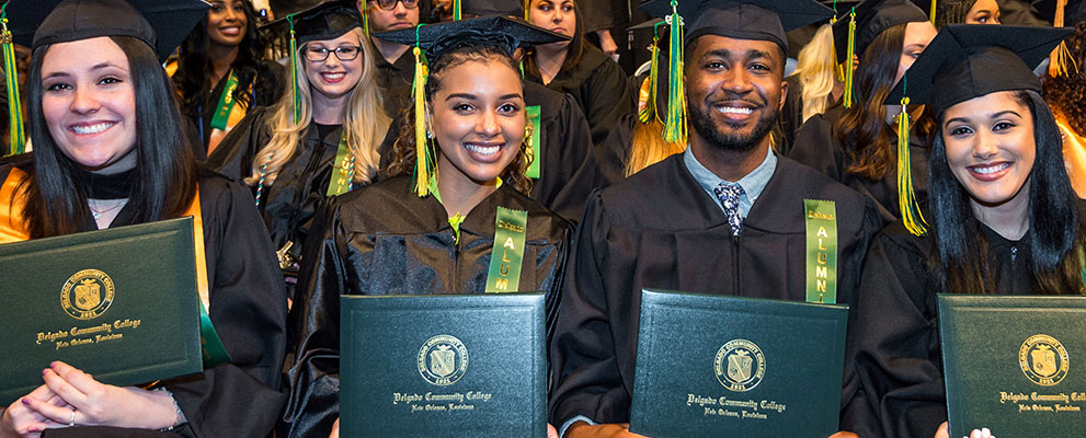 Students smiling and holding diplomas at graduation