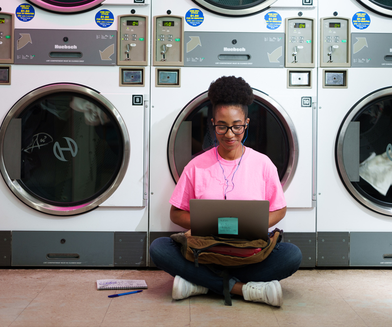 female students on a laptop in a laundromat