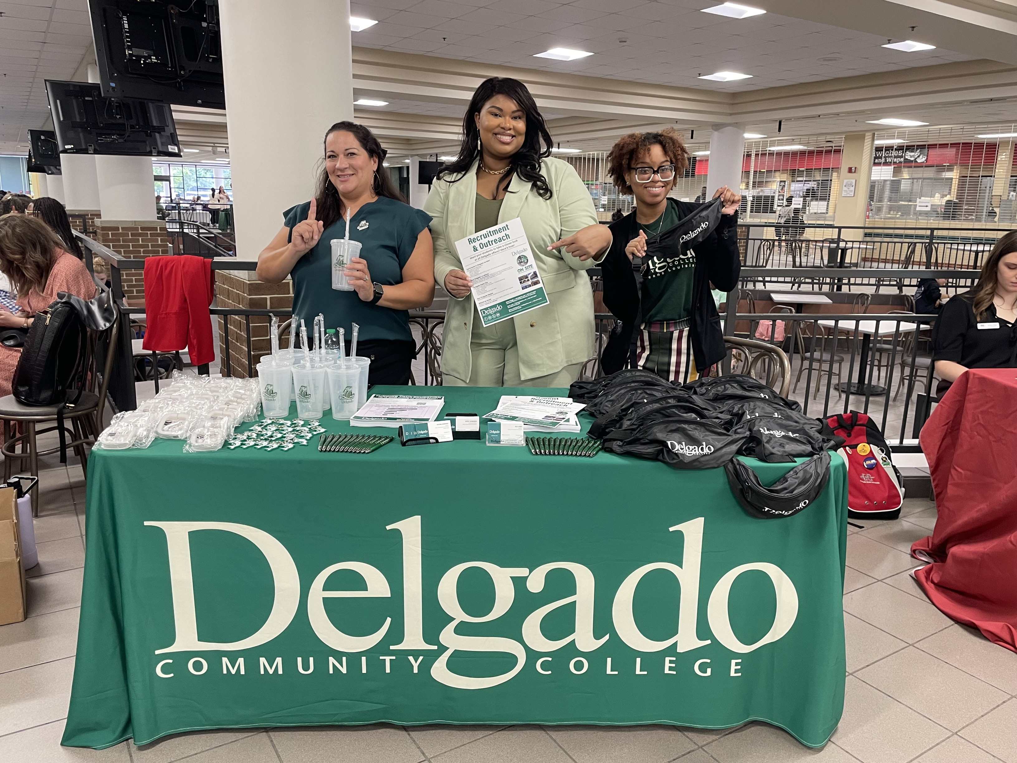 Enrollment team members at a table with Delgado swag.