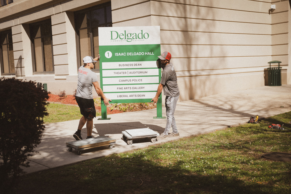 Installers from OPA Signs move a sign for Building 1 into position