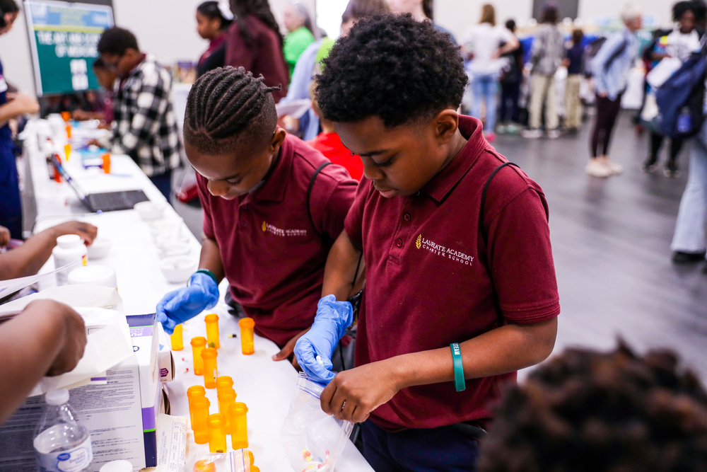 Two students wearing gloves handle tubes used in science experiments