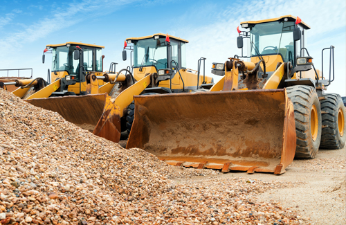 heavy equpiment parked by pile of gravel